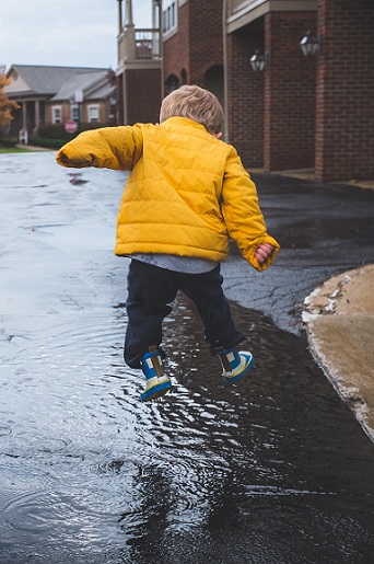 Child jumping in puddles. Photo by Neonbrand on Unsplash photo website.