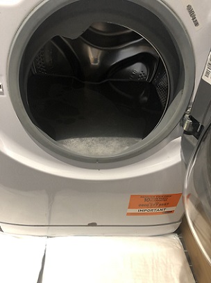Faulty washing machine full of water with FloodSax alternative sandbags protecting the floor